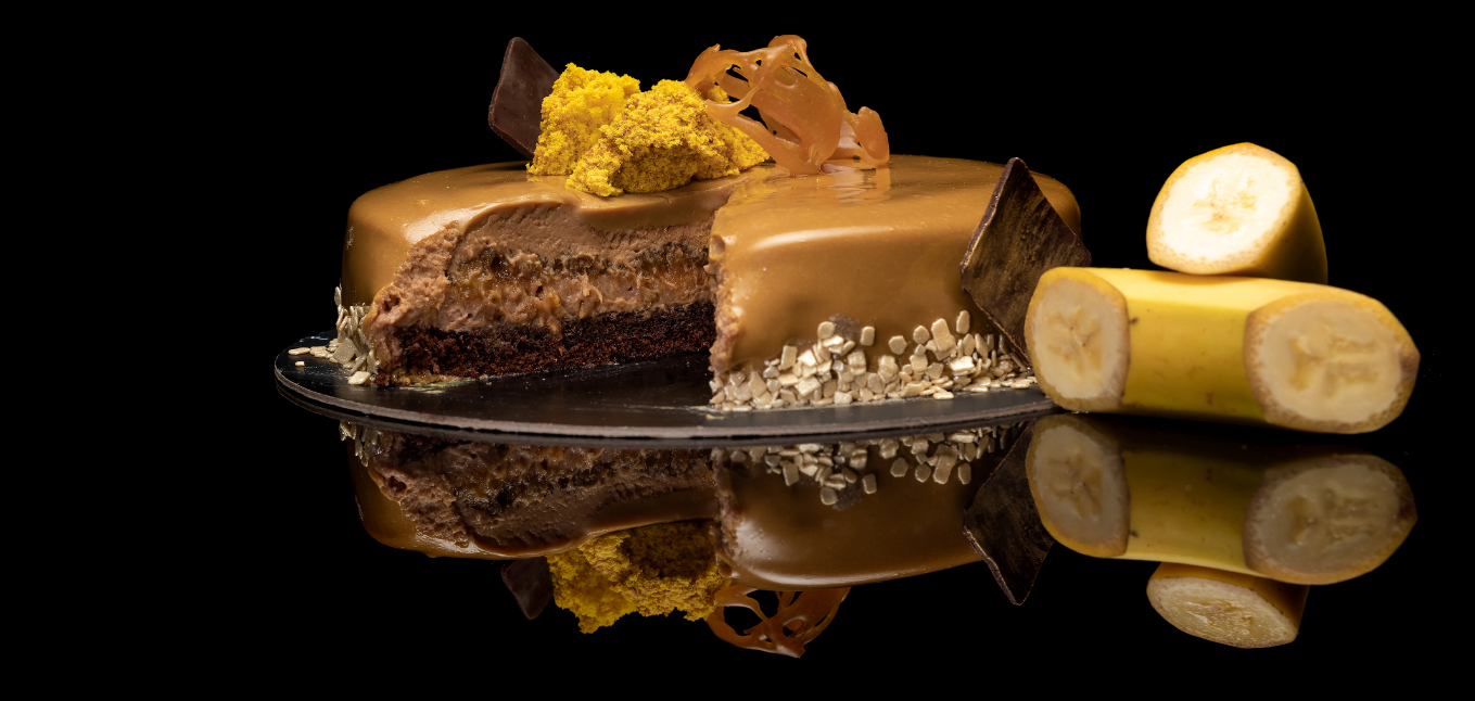 Tort cu banane Sweetium Sărutare din banane caramelizate cu conținut redus de zahăr cu blat brownie, mousse de ciocolată cu lapte, mousse de ciocolată cu caramel și banane caramelizate.
